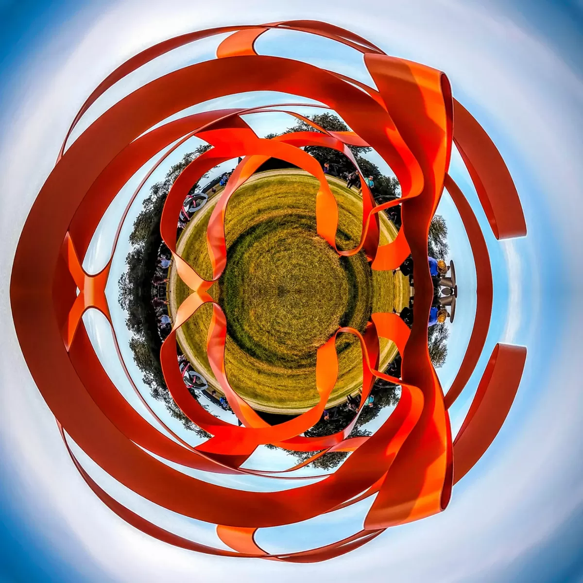 Circular little-planet photo wrapped in orange sculpture ribbons